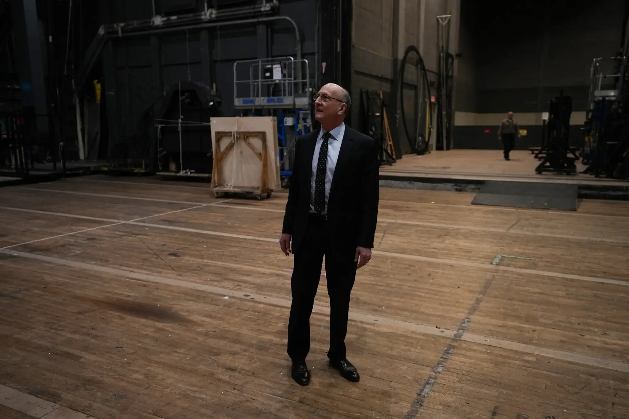 Peter Gelb standing alone in a vast backstage space, looking for clues